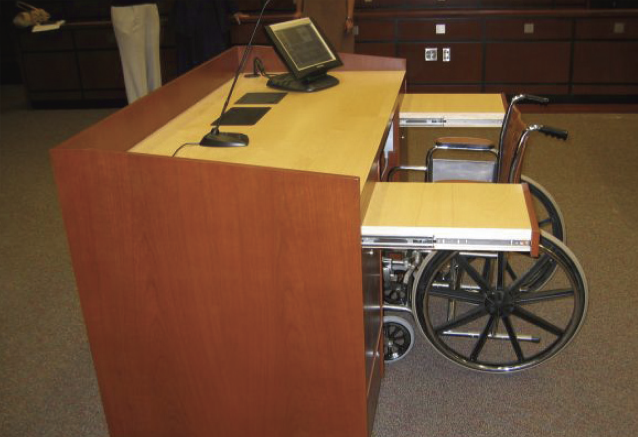 Photo showing wheelchair accessible podium with shelves and monitor